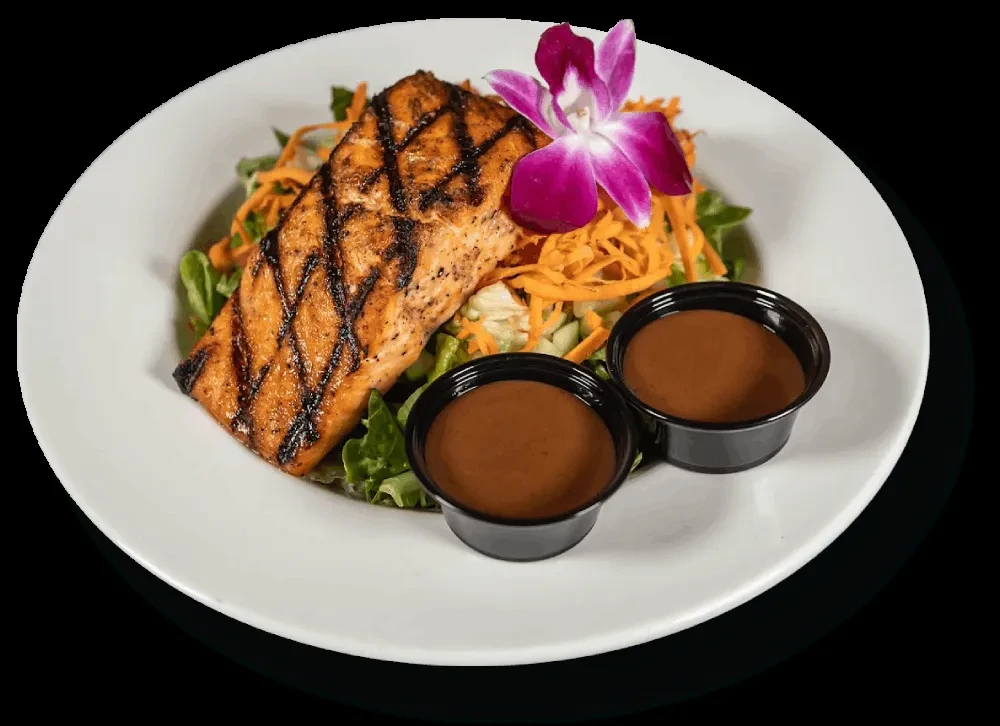 Grilled salmon, greens, orchid, and sauce on white plate, black background.