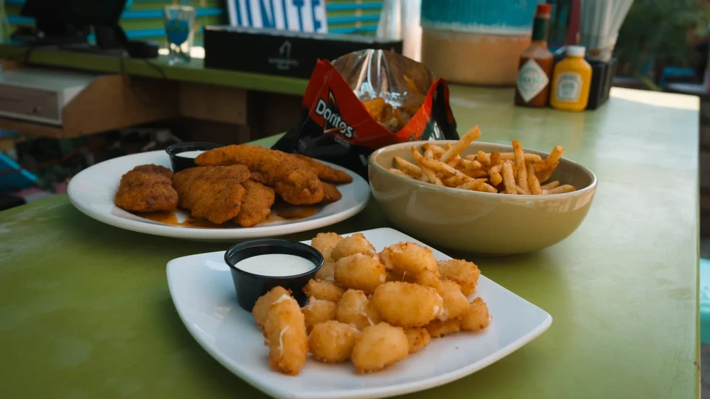 Fried food spread: cheese curds, chicken, fries, and Doritos at a bar.