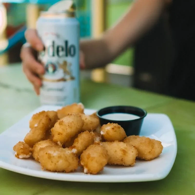 Golden fried cheese curds, dipping sauce, and Modelo beer can.
