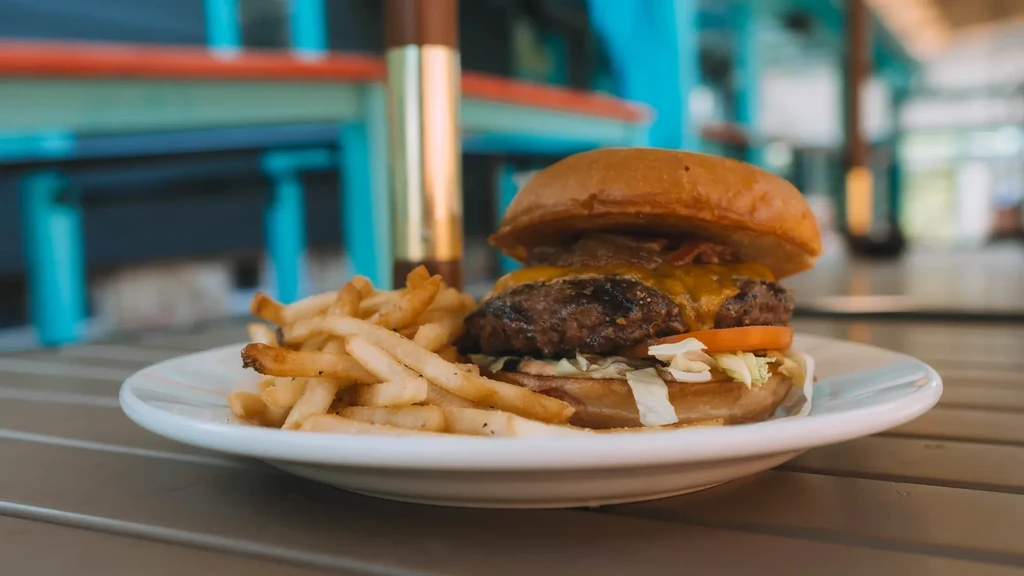Cheeseburger with melted cheese, bacon, lettuce, tomato, and golden fries.