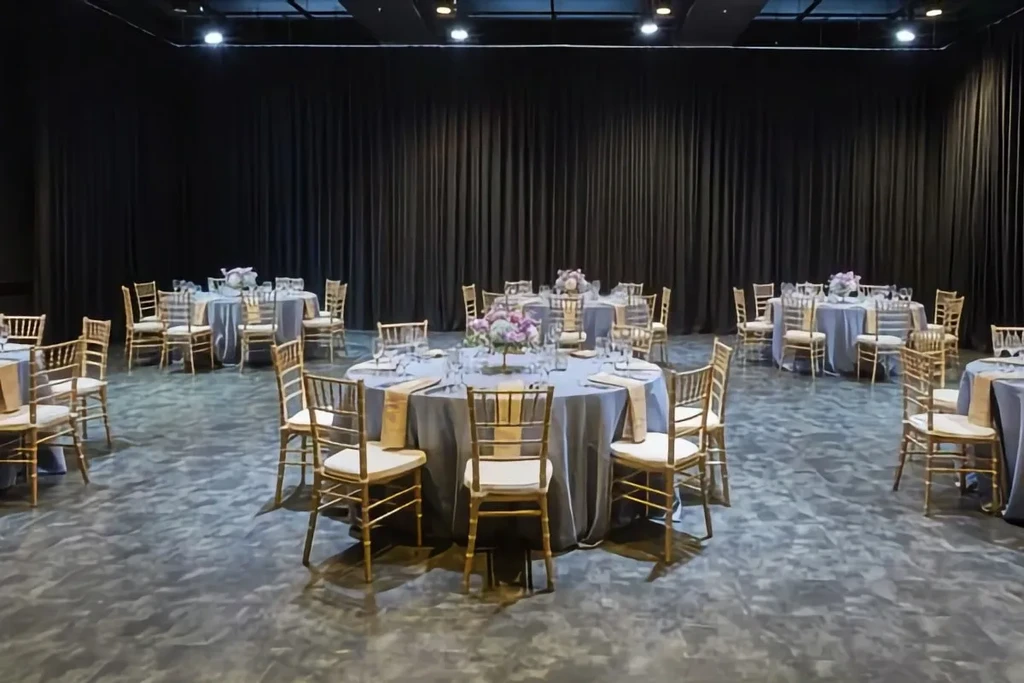 Empty event space with set tables, floral centerpieces, and gold chairs.
