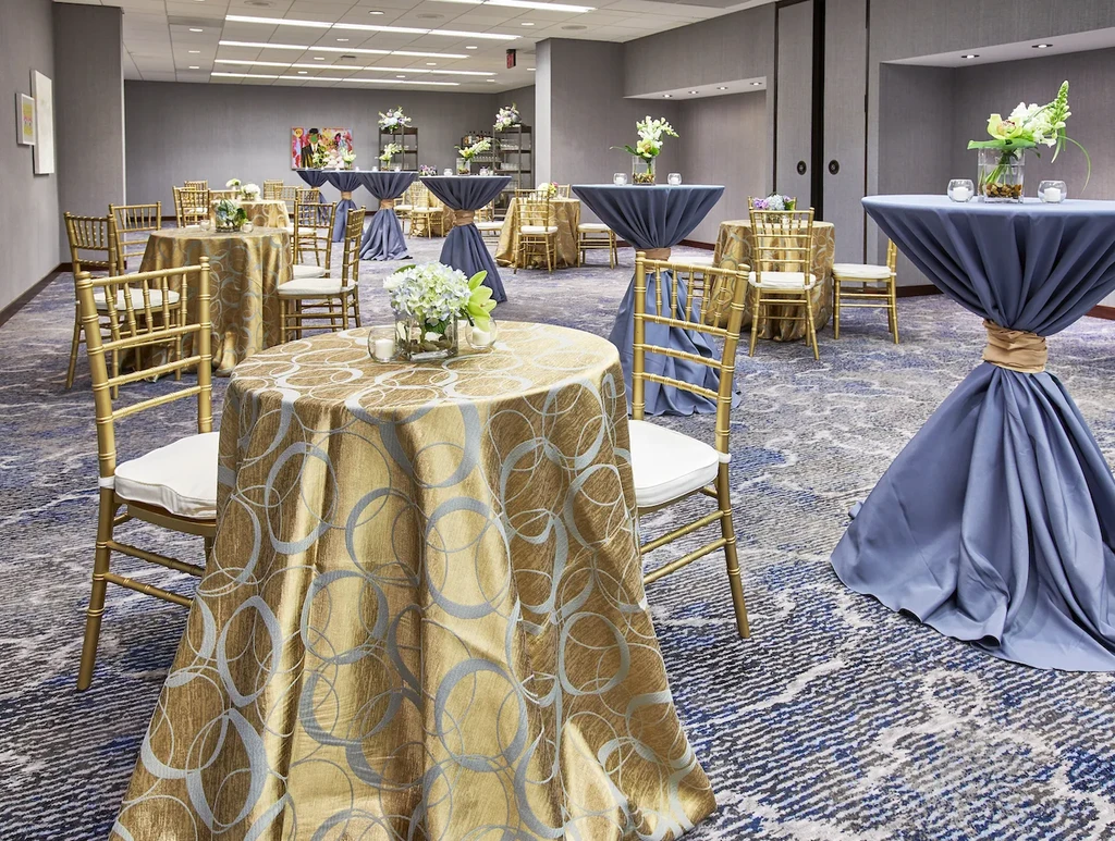 Elegant event space with golden and blue tables, Chiavari chairs, flowers.