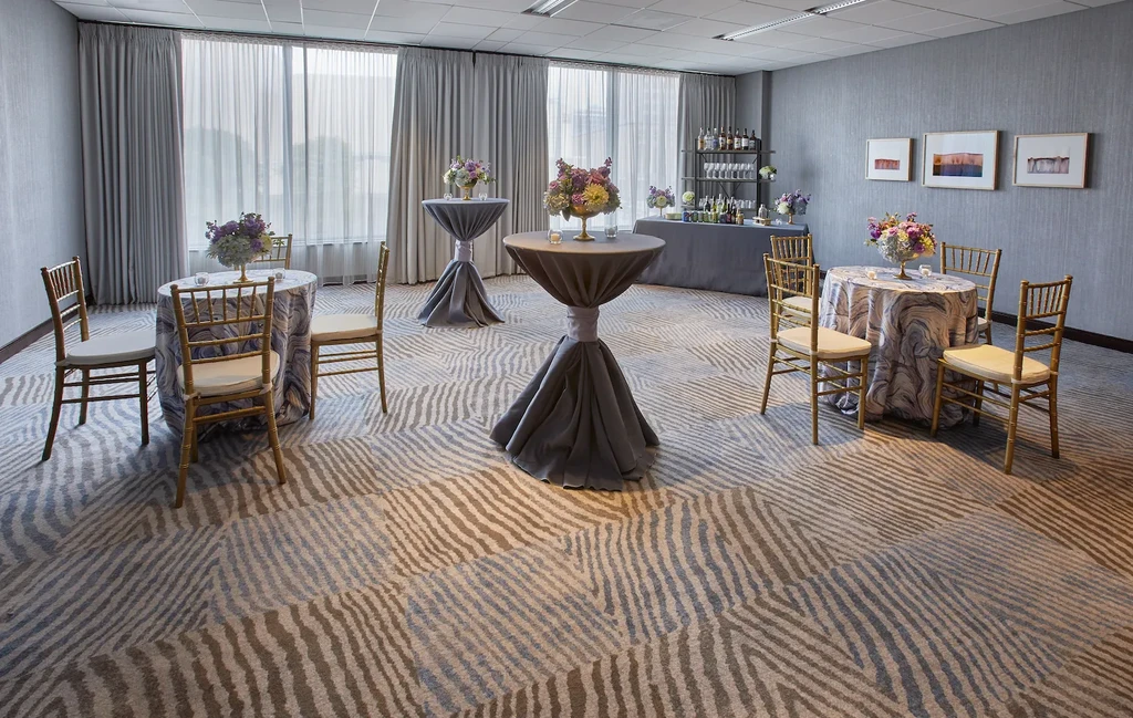 Empty modern event lounge with decorated tables, gold chairs, and bar.