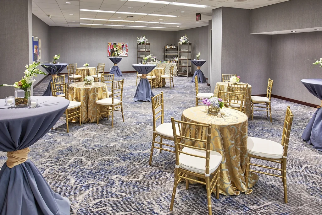 Elegant event hall with round tables, Chiavari chairs, and bar stations.