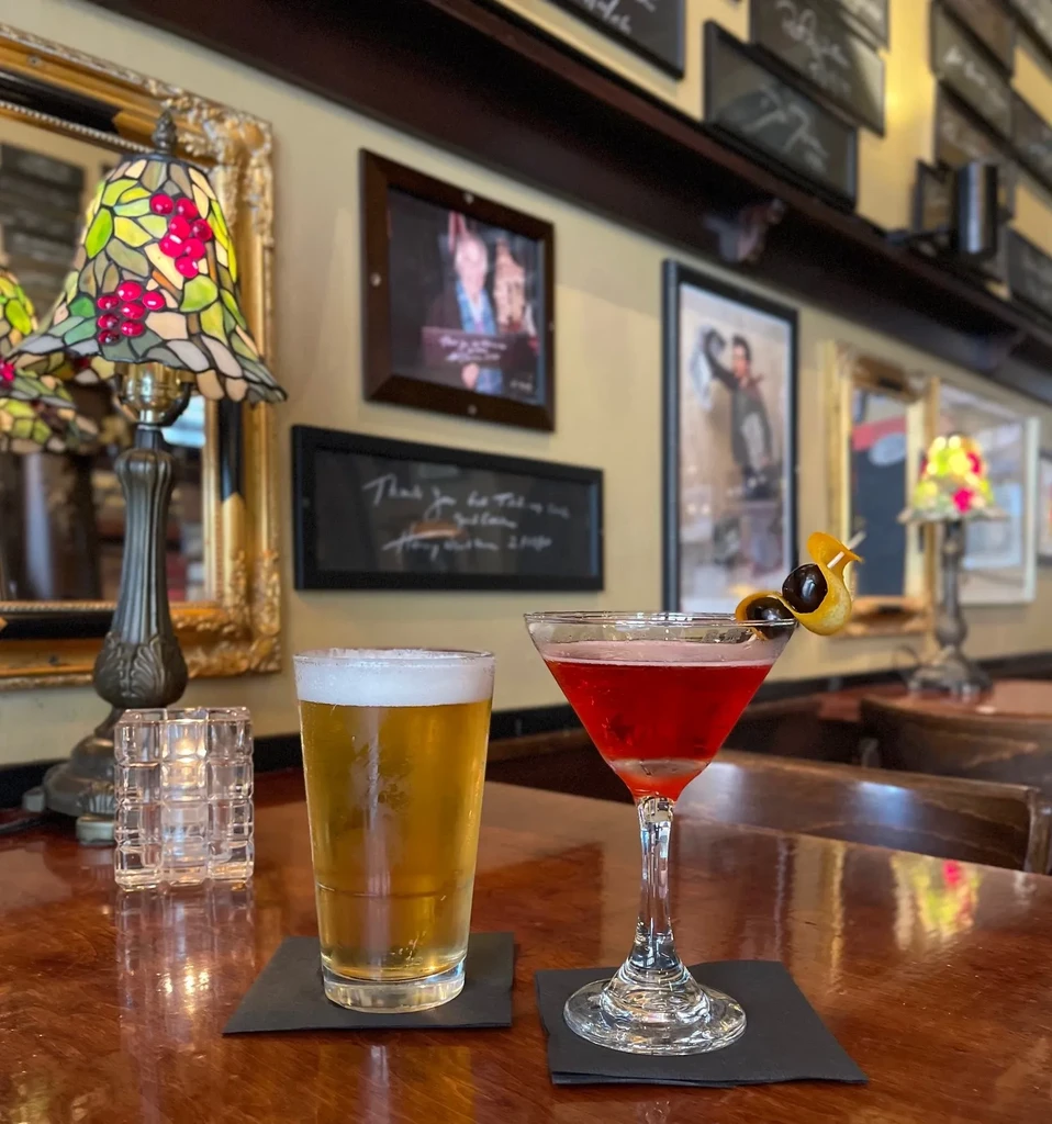 A pint of beer and a red cocktail on a bar counter.