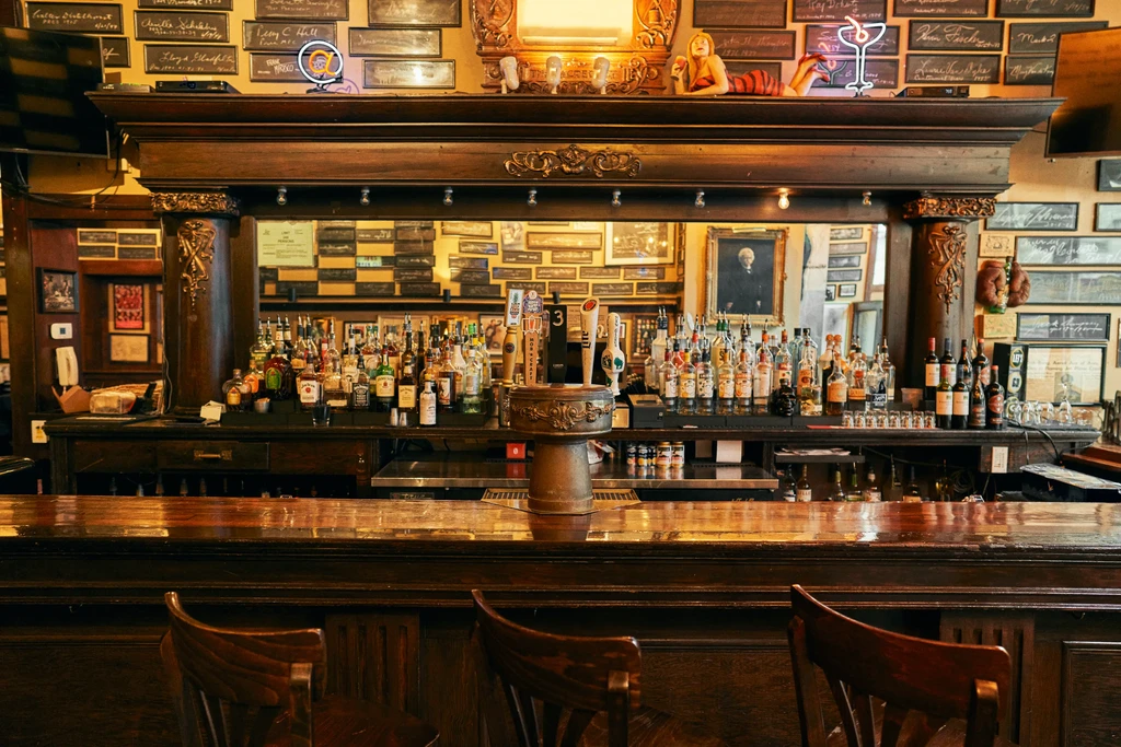 Well-stocked classic dark wood bar with liquor bottles and memorabilia.
