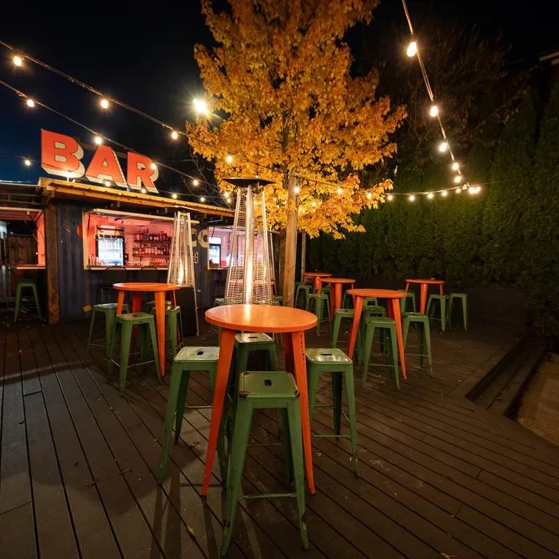 Night view of an outdoor bar with tables, container bar, and lights.