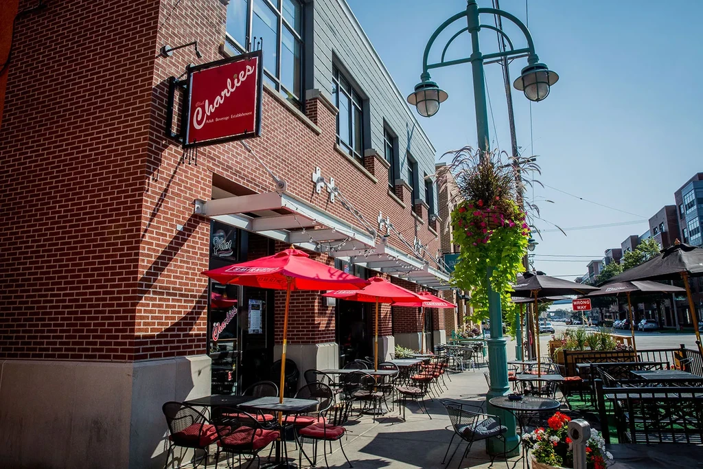 Charlie's bar: brick building, red umbrellas, outdoor seating, flowering streetlamp.