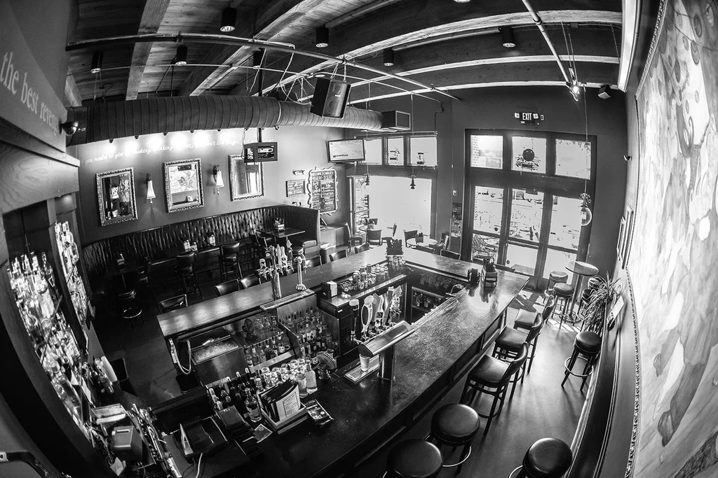 Empty black and white restaurant interior with a long bar and seating.