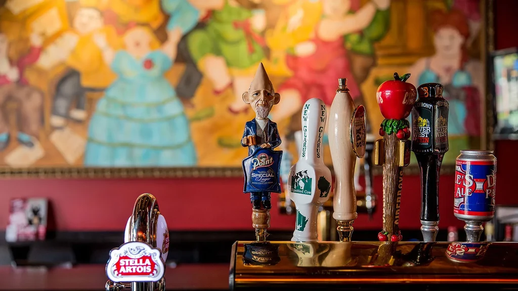 Colorful beer tap handles and a beer can on a polished bar.