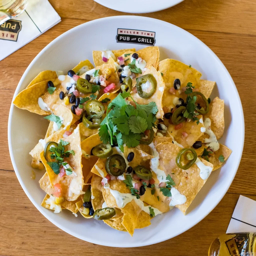 Close-up overhead of loaded nachos with cheese, beans, corn, and jalapeños.
