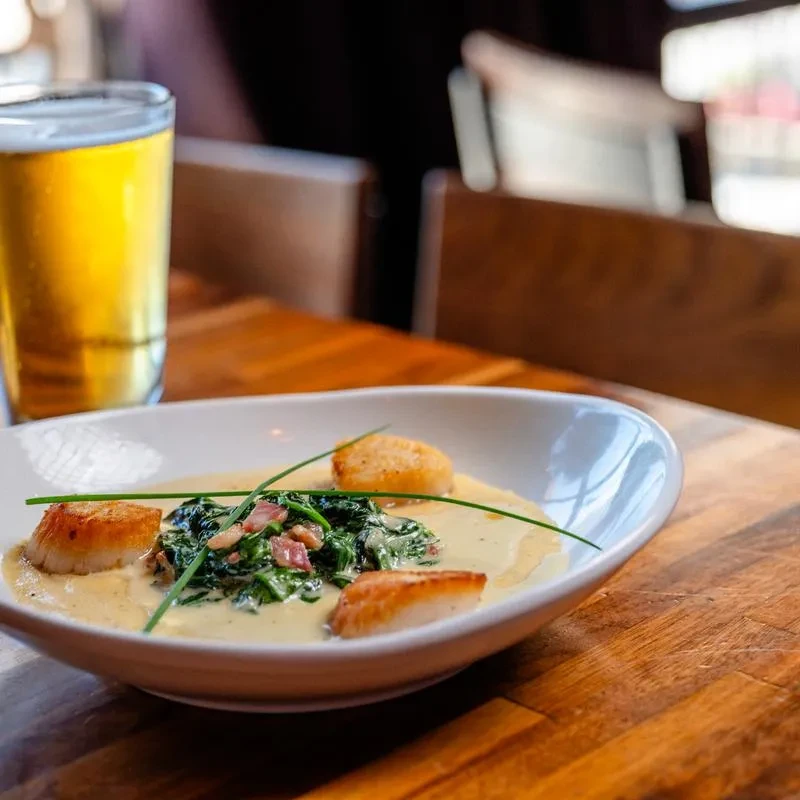 Pan-seared scallops with creamy sauce, spinach, chives, and beer.