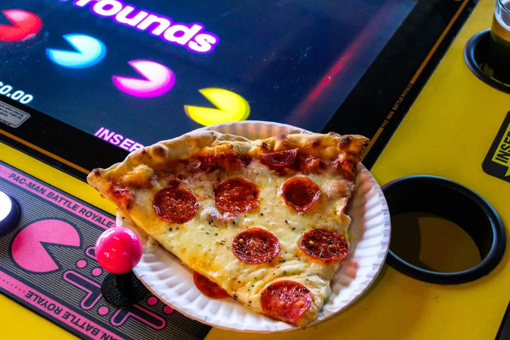 Pepperoni pizza slice on Pac-Man arcade control panel with joystick.
