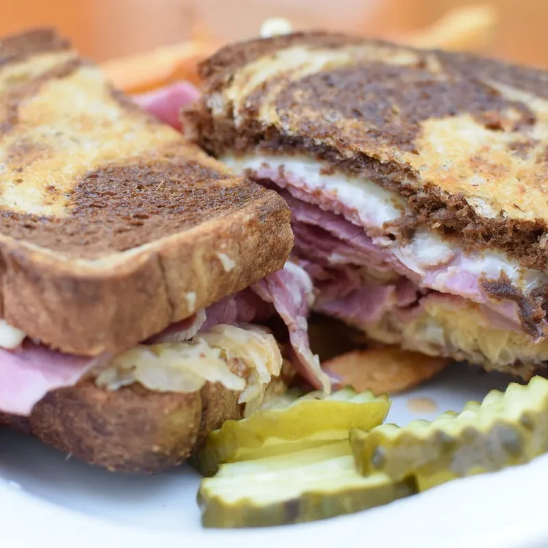 Half a Reuben sandwich with corned beef, sauerkraut, and pickles.