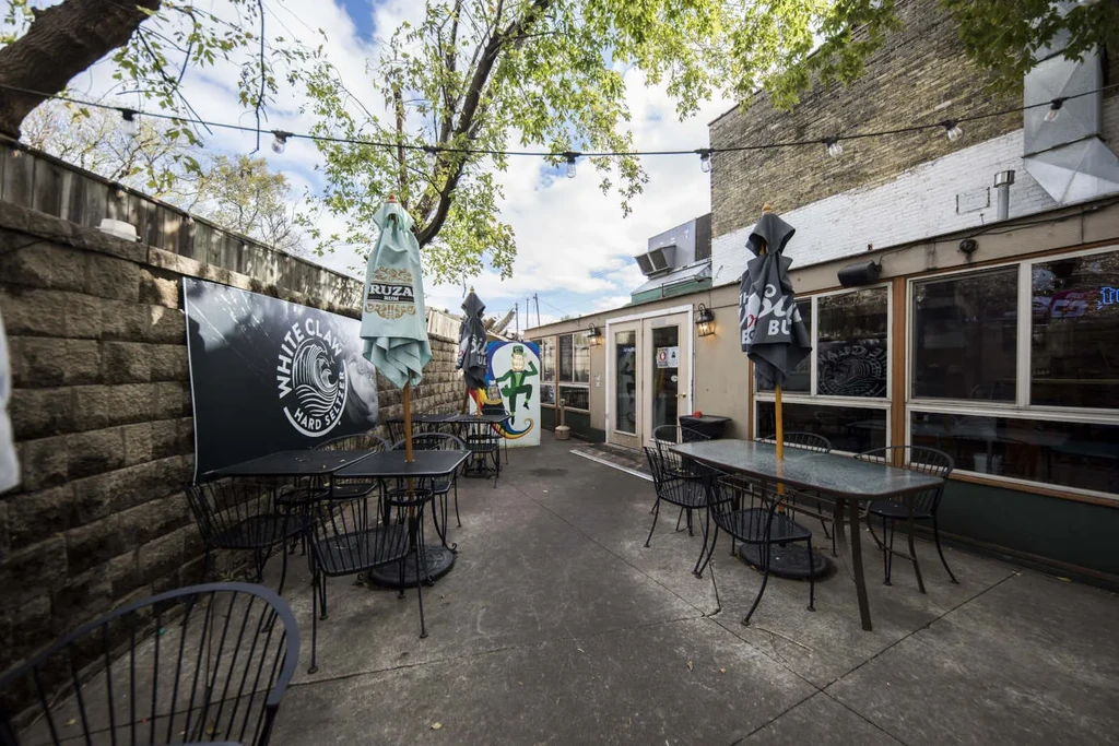 Outdoor restaurant patio with tables, string lights, and prominent beverage branding.