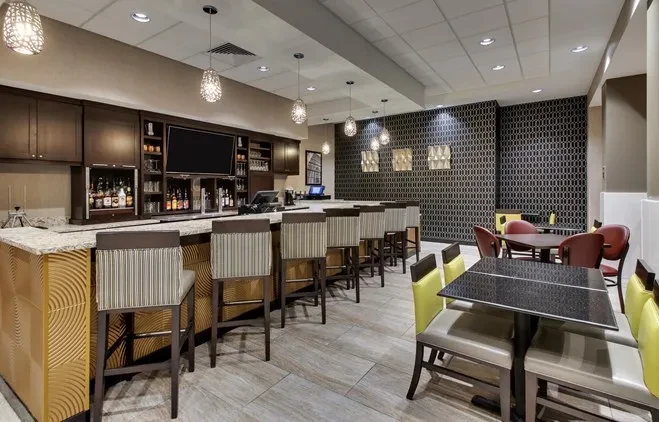 Modern bar and dining area with gold-paneled bar and colorful seating.