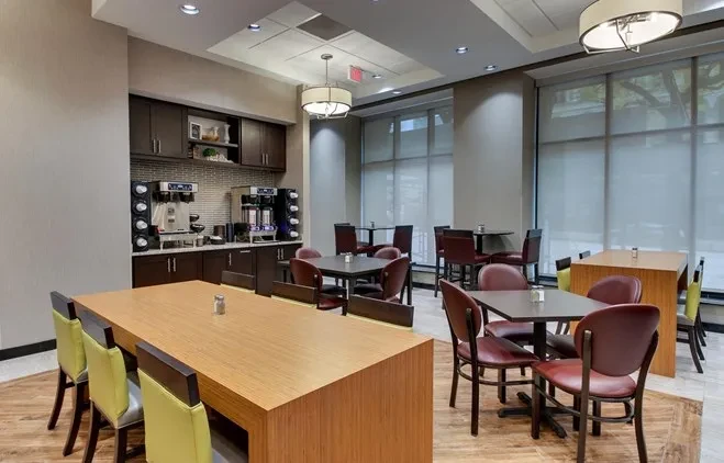 Modern hotel breakfast lounge with beverage counter and varied seating.
