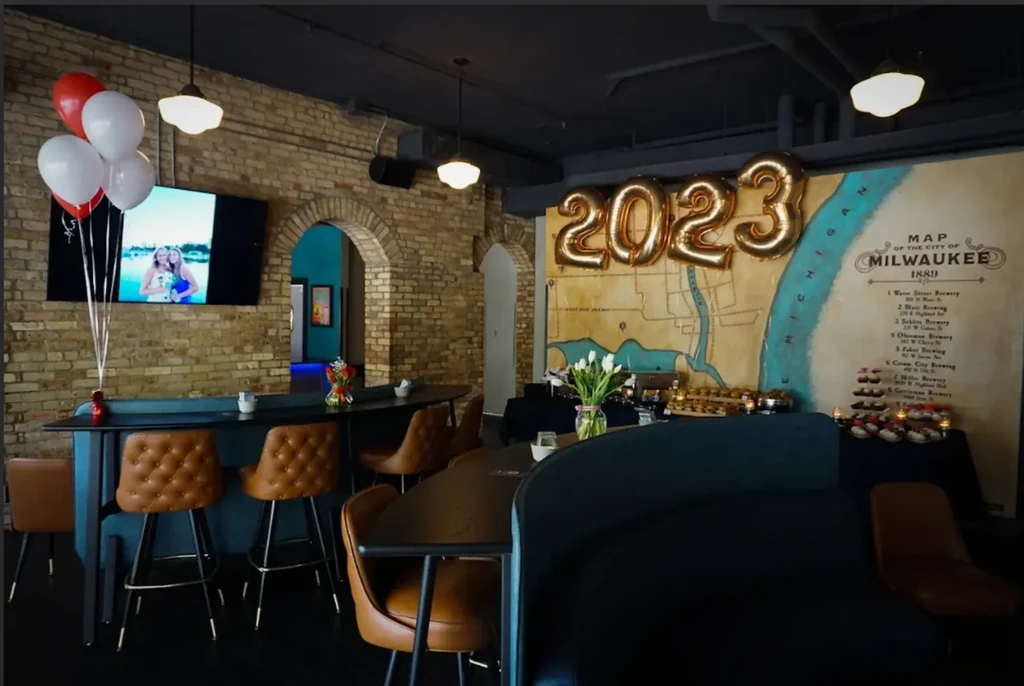 Modern bar interior with exposed brick, Milwaukee map, and 2023 balloons.