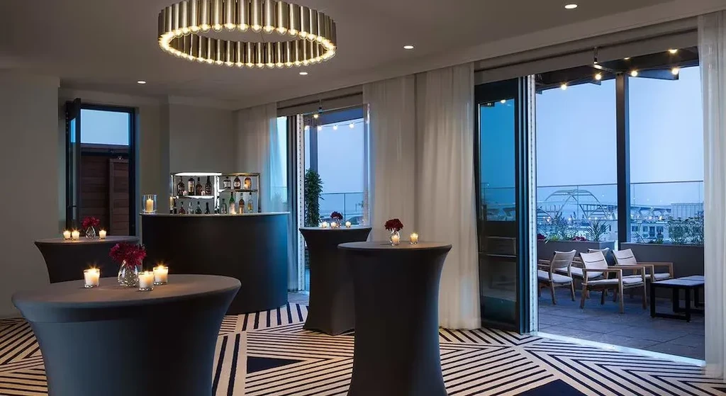 Curved bar, geometric carpet, and patio city skyline view at dusk.
