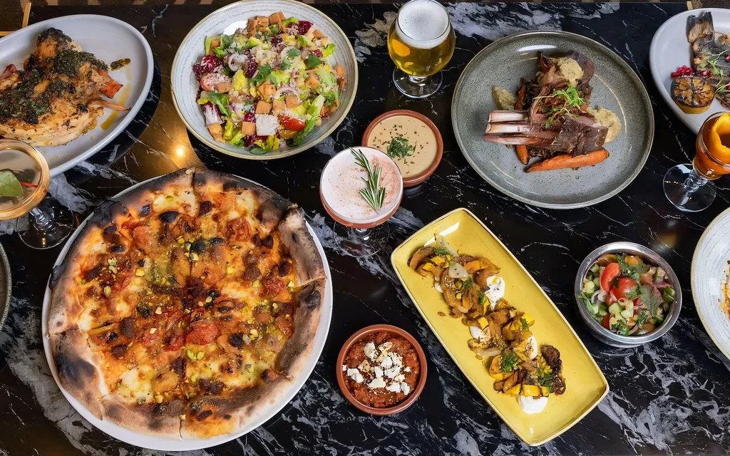 Gourmet dishes and drinks on a marble table, overhead view.