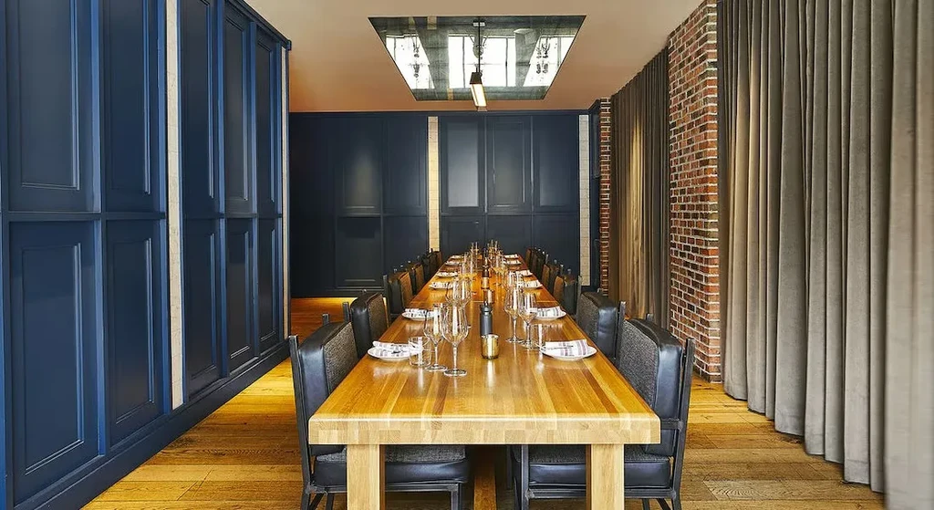 Modern private dining room with a long, set wooden communal table.