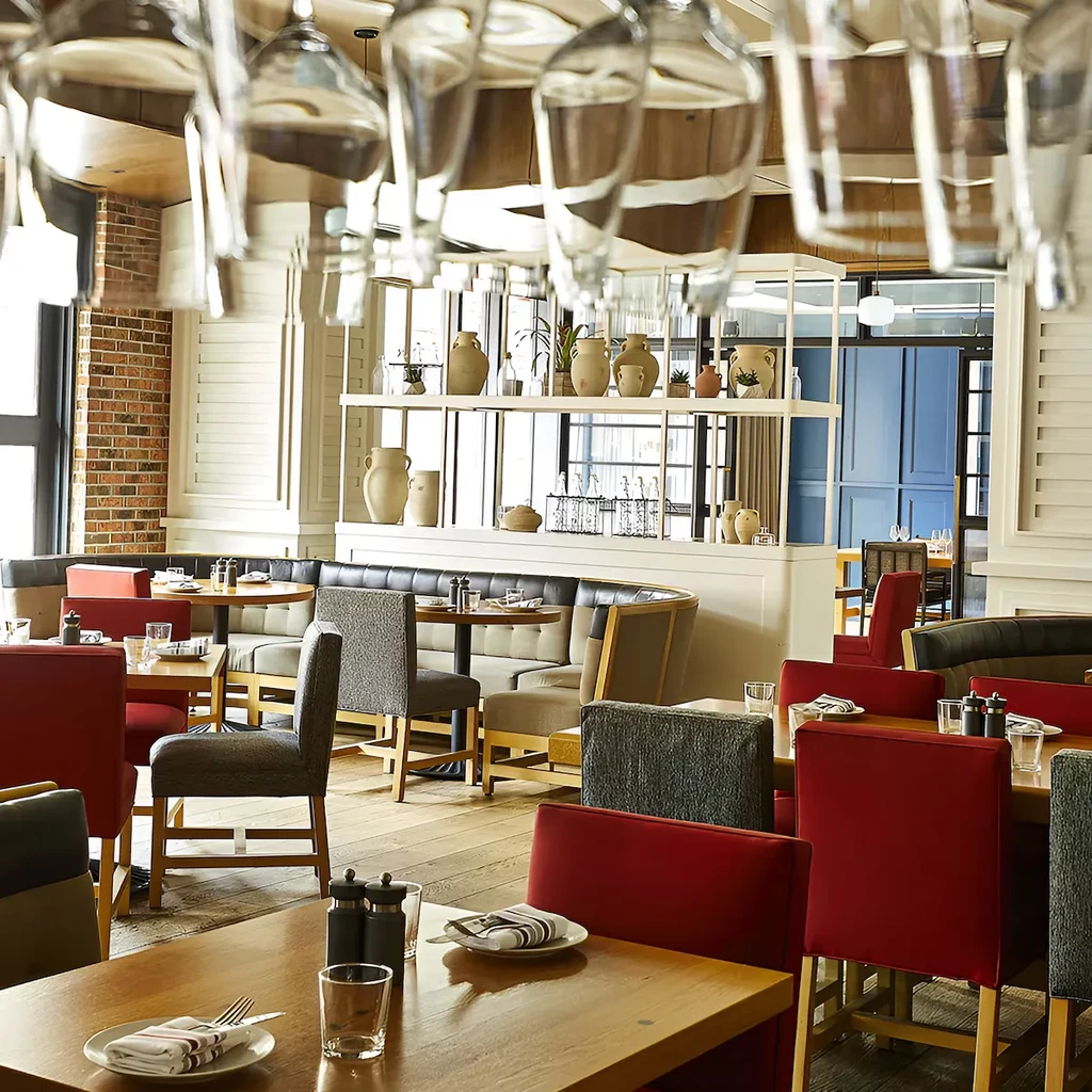 Empty, contemporary restaurant interior with diverse seating and hanging glasses.