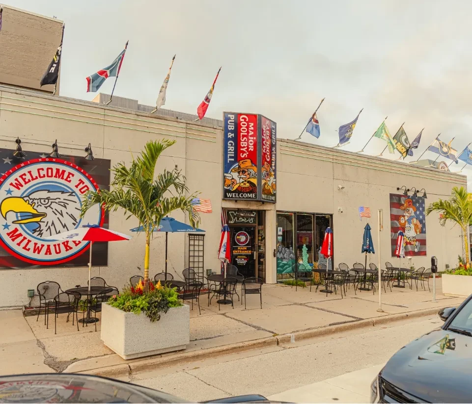 Major Goolsby's Pub & Grill exterior with patio, umbrellas, banners, flags.