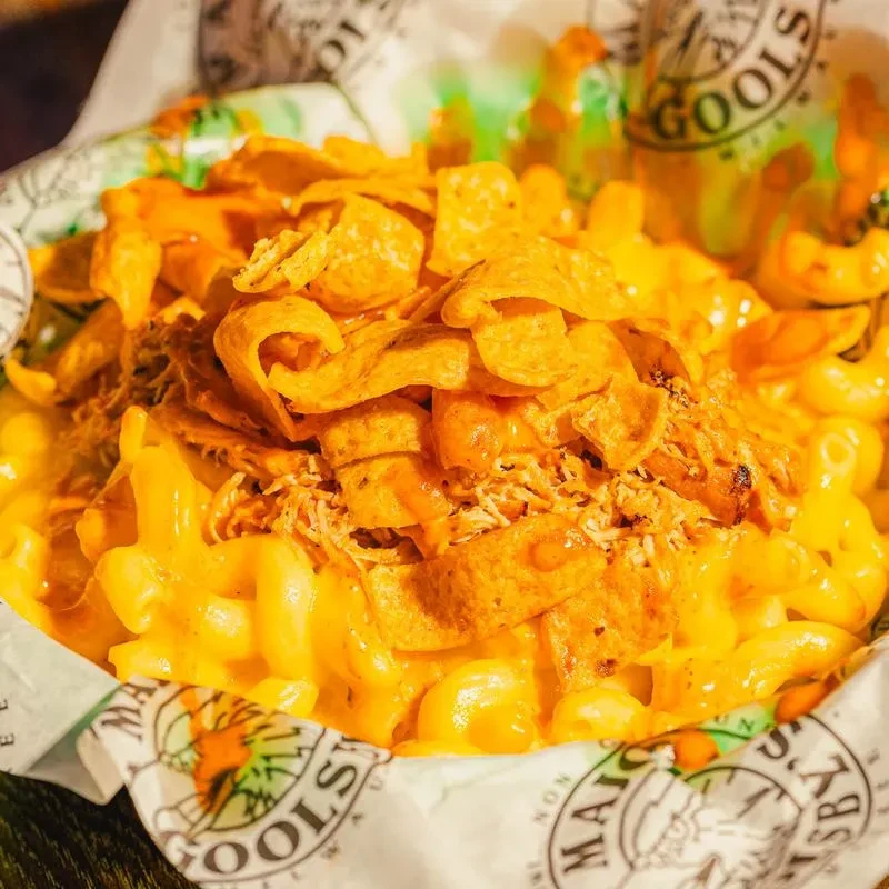 Mac and cheese with crispy chips, shredded meat, and MACOOL'S logo.