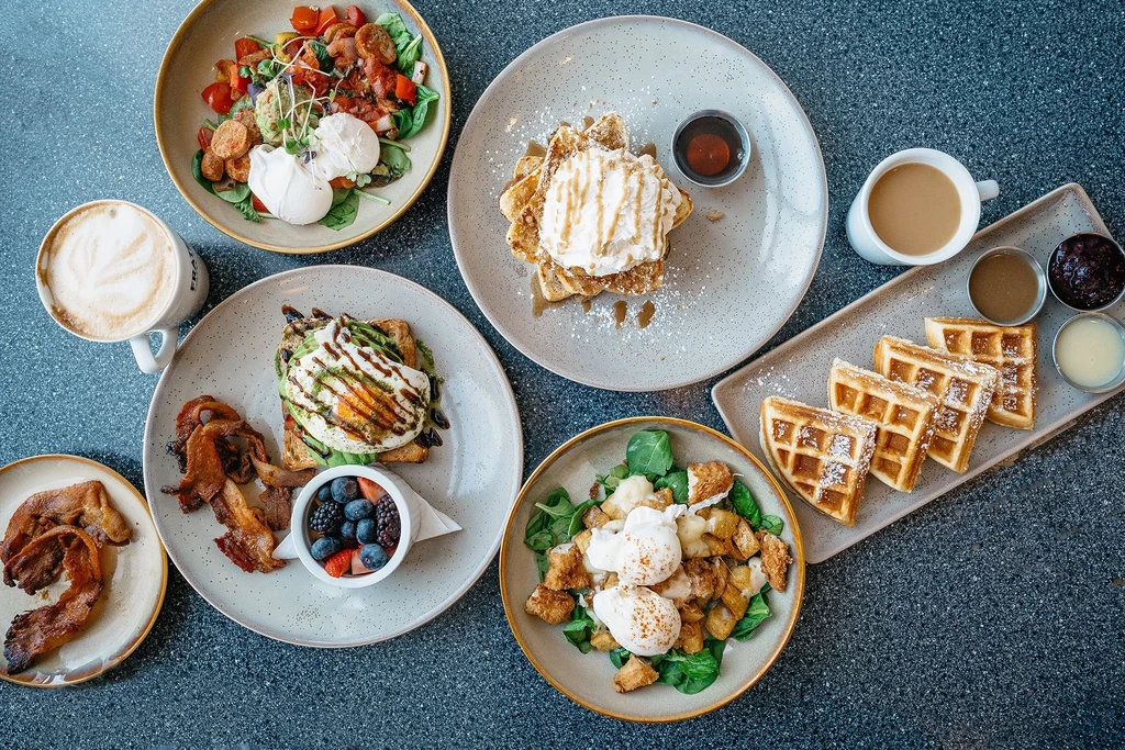 Flat lay of assorted breakfast and brunch dishes on a dark table.