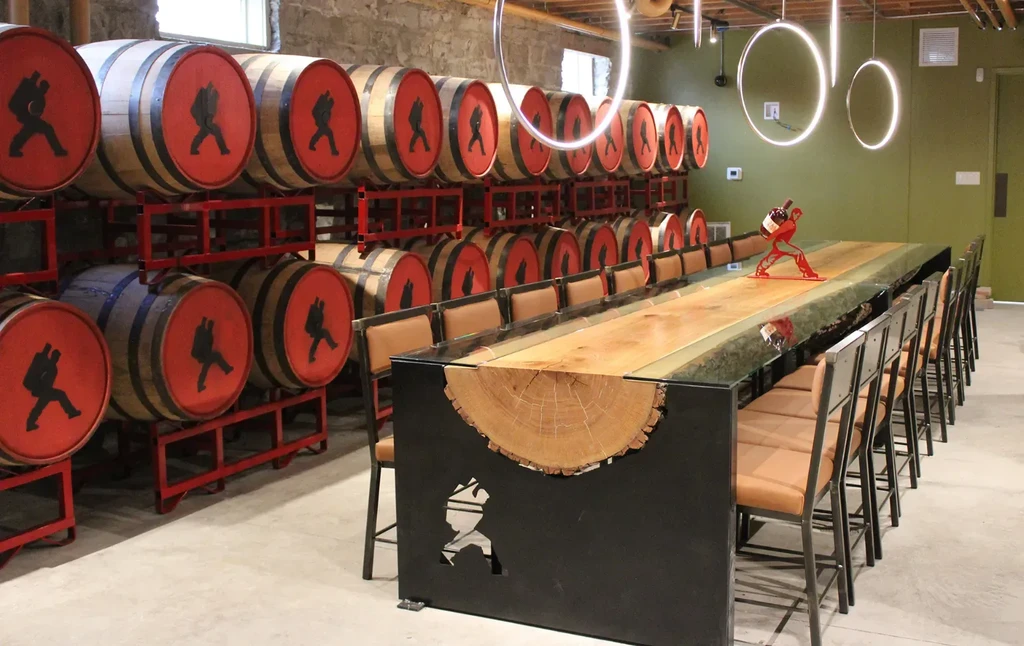Distillery tasting room with stacked barrels and a long live-edge table.