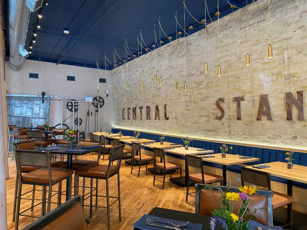 Industrial-chic restaurant with "CENTRAL STAN" sign and blue banquette.