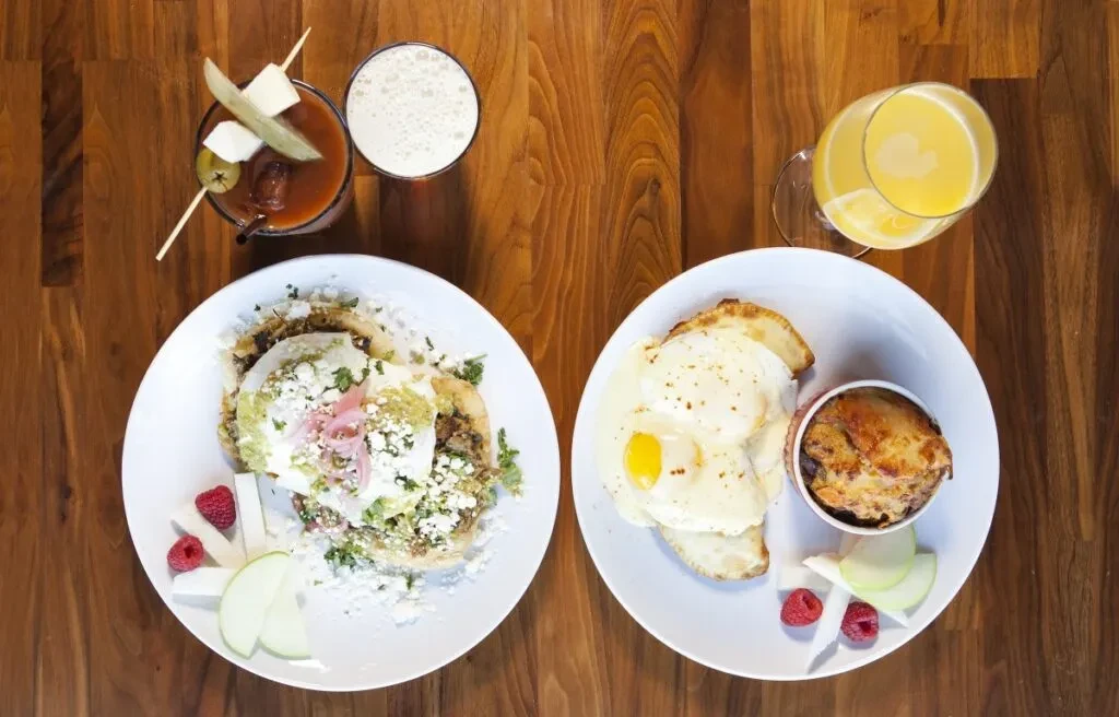 Breakfast plates: savory tortillas, sunny-side-up eggs, drinks on wood.