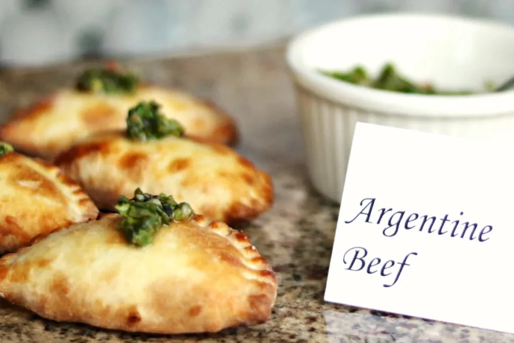 Baked empanadas with green sauce, next to 'Argentine Beef' card.