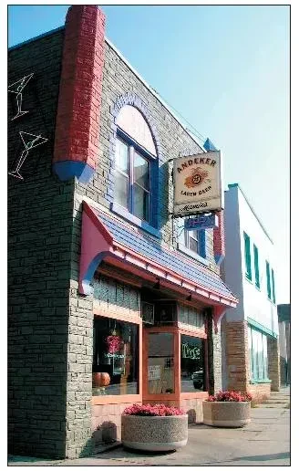 Building exterior with dark stone, red brick, striped awning, and beer sign.