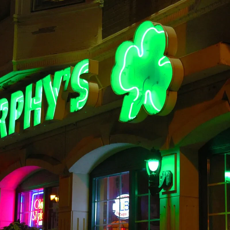 Building exterior at night with glowing green "URPHY'S" neon and shamrock sign.