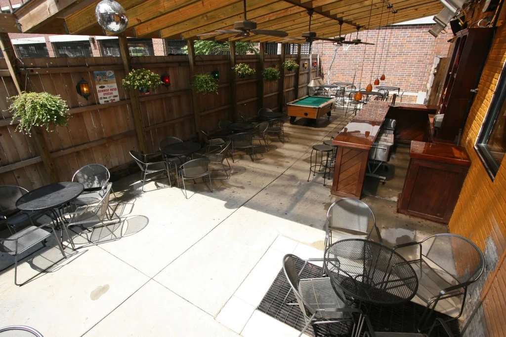 Empty beer garden patio with tables, bar, and pool table.