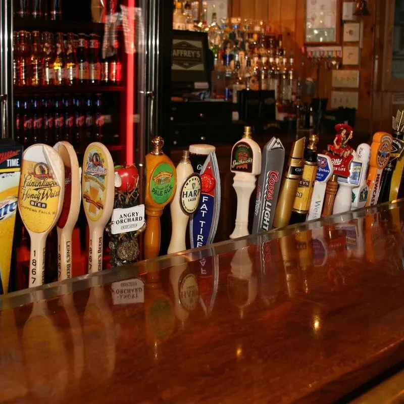 Close-up of many diverse beer tap handles on a bar counter.