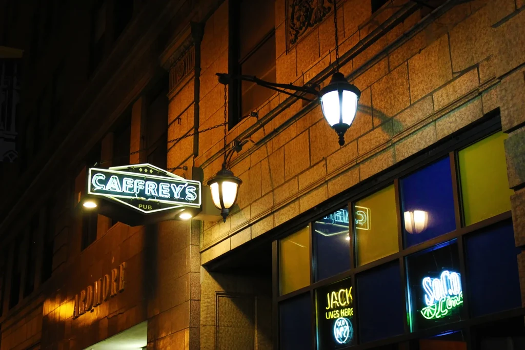 Retro 'CAFFREYS PUB' neon sign glows brightly on a building at night.