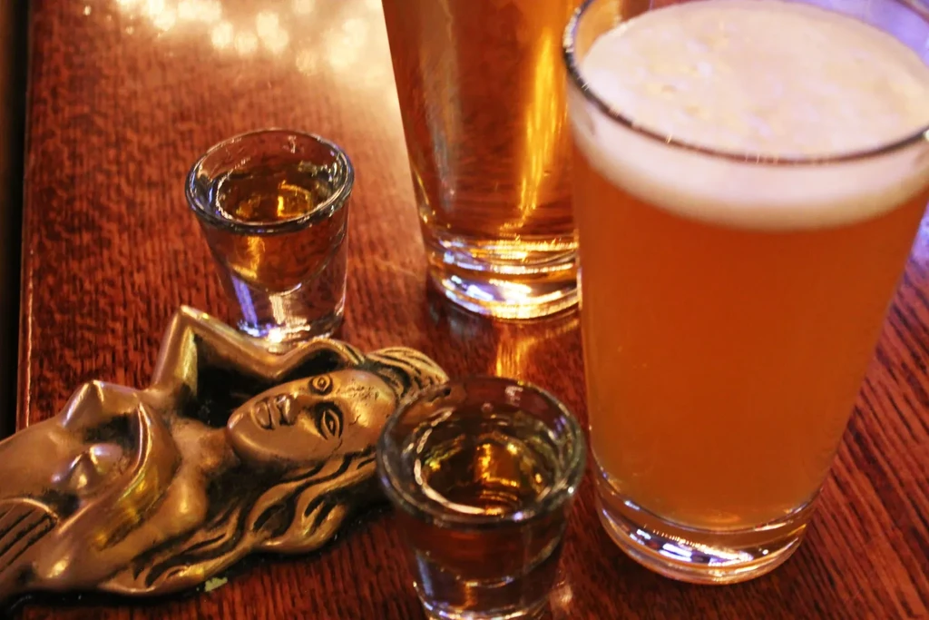 Beer, shot glasses, and a stylized female bottle opener on wood.