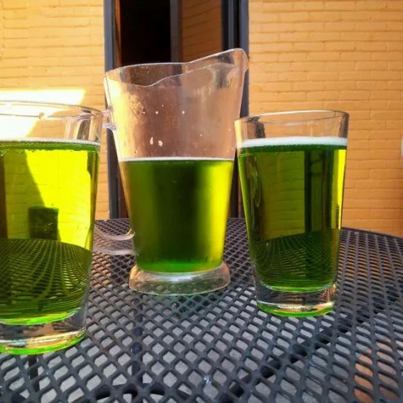 Three glass vessels with green foamy liquid on an outdoor table.
