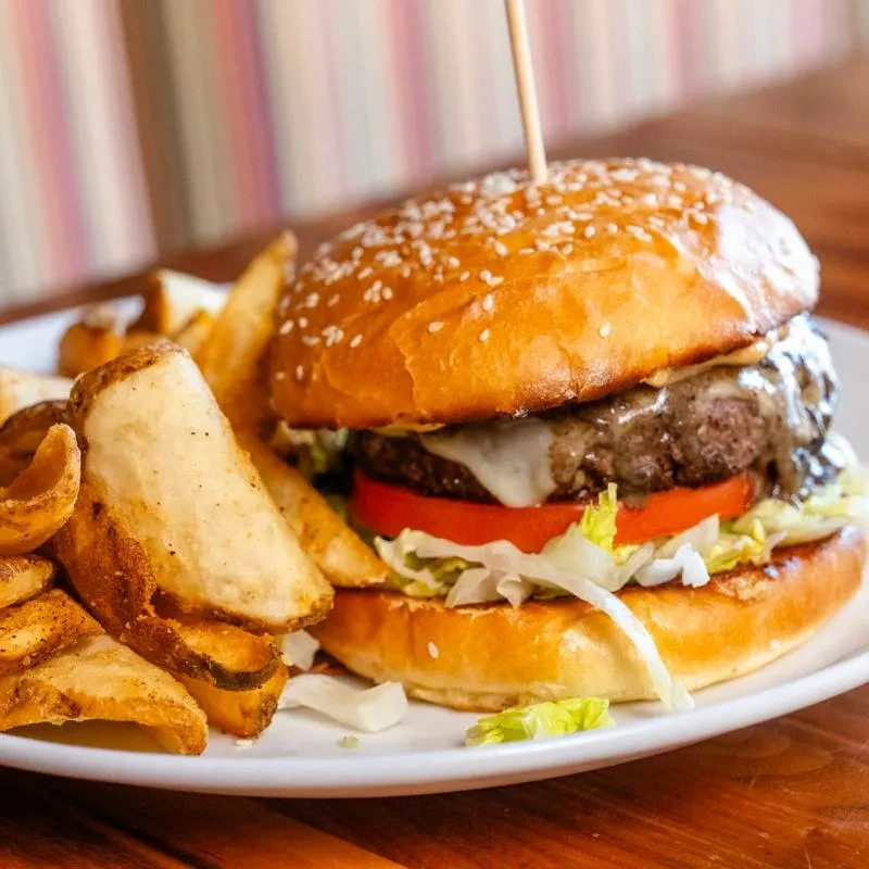 Cheeseburger with melted cheese, tomato, lettuce, and potato wedge fries.