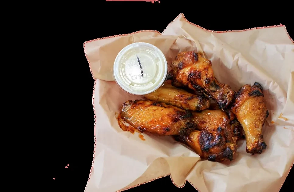 Grilled chicken wings and drumettes in a paper container with dipping sauce.