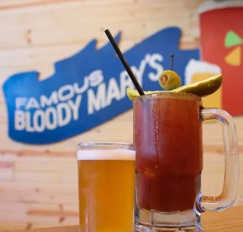 Bloody Mary with pickle, beer, and "FAMOUS BLOODY MARY'S" sign.