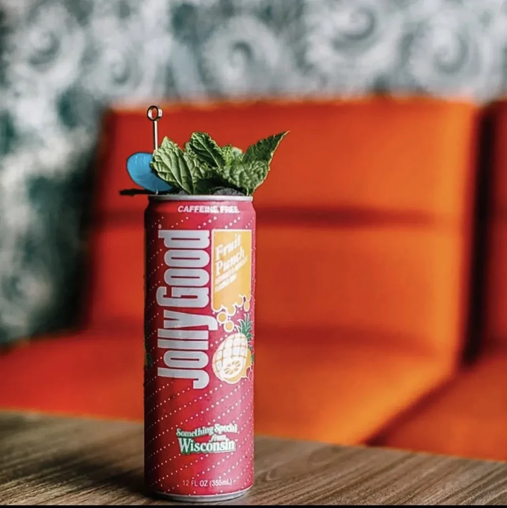 Red Jolly Good Fruit Punch can with mint and stirrers on wood.