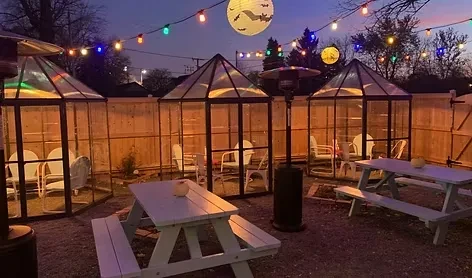 Outdoor dining with private igloo structures, picnic tables, and a bat lantern.