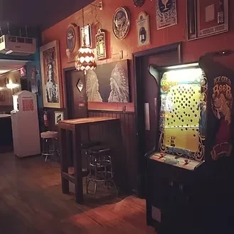 Dimly lit bar interior with vintage Skee-Ball game and rustic decor.