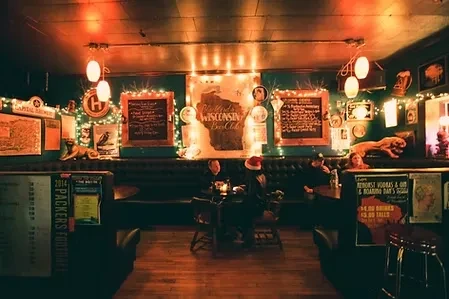 Cozy, dimly lit bar interior with eclectic decorations and seated patrons.