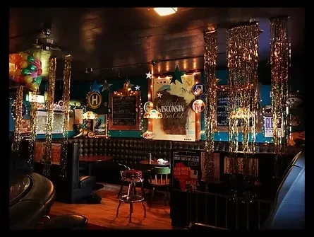 Cozy, dimly lit bar interior with booth seating and festive tinsel.