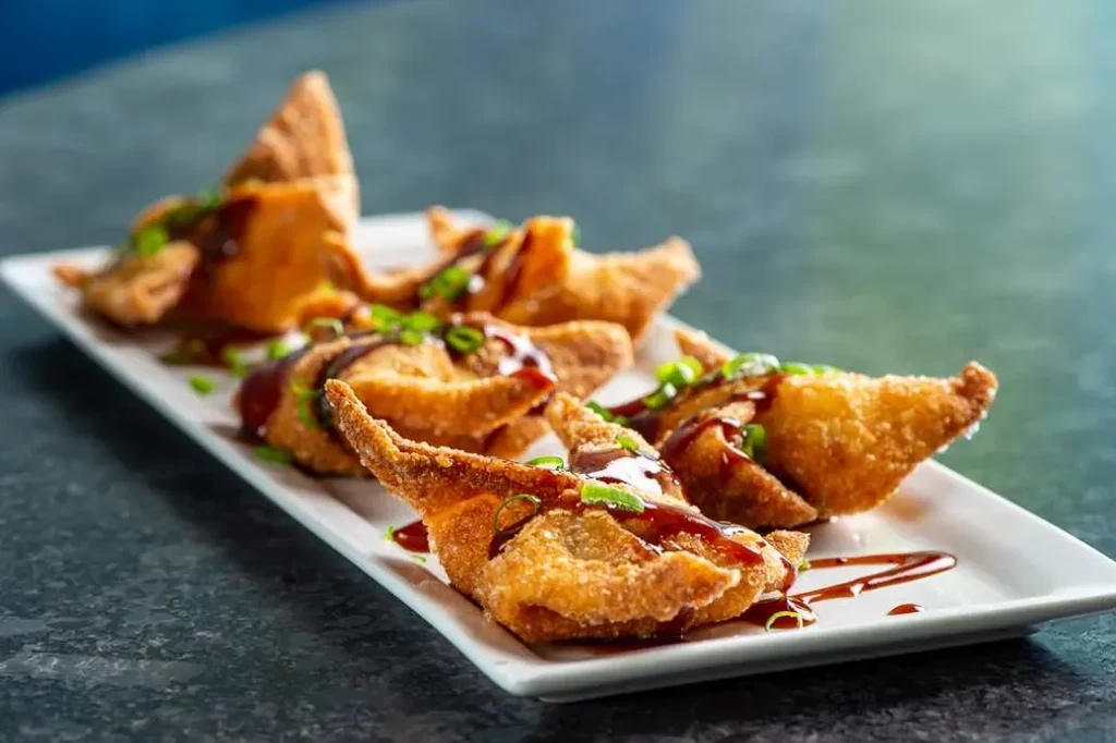 Crispy golden-brown fried appetizers with dark glaze and green onions.