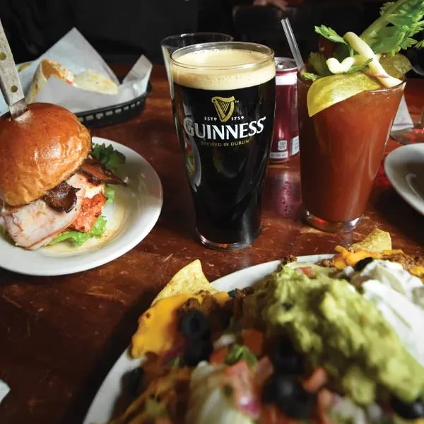 Tabletop scene with Guinness, burger, Bloody Mary, and nachos.